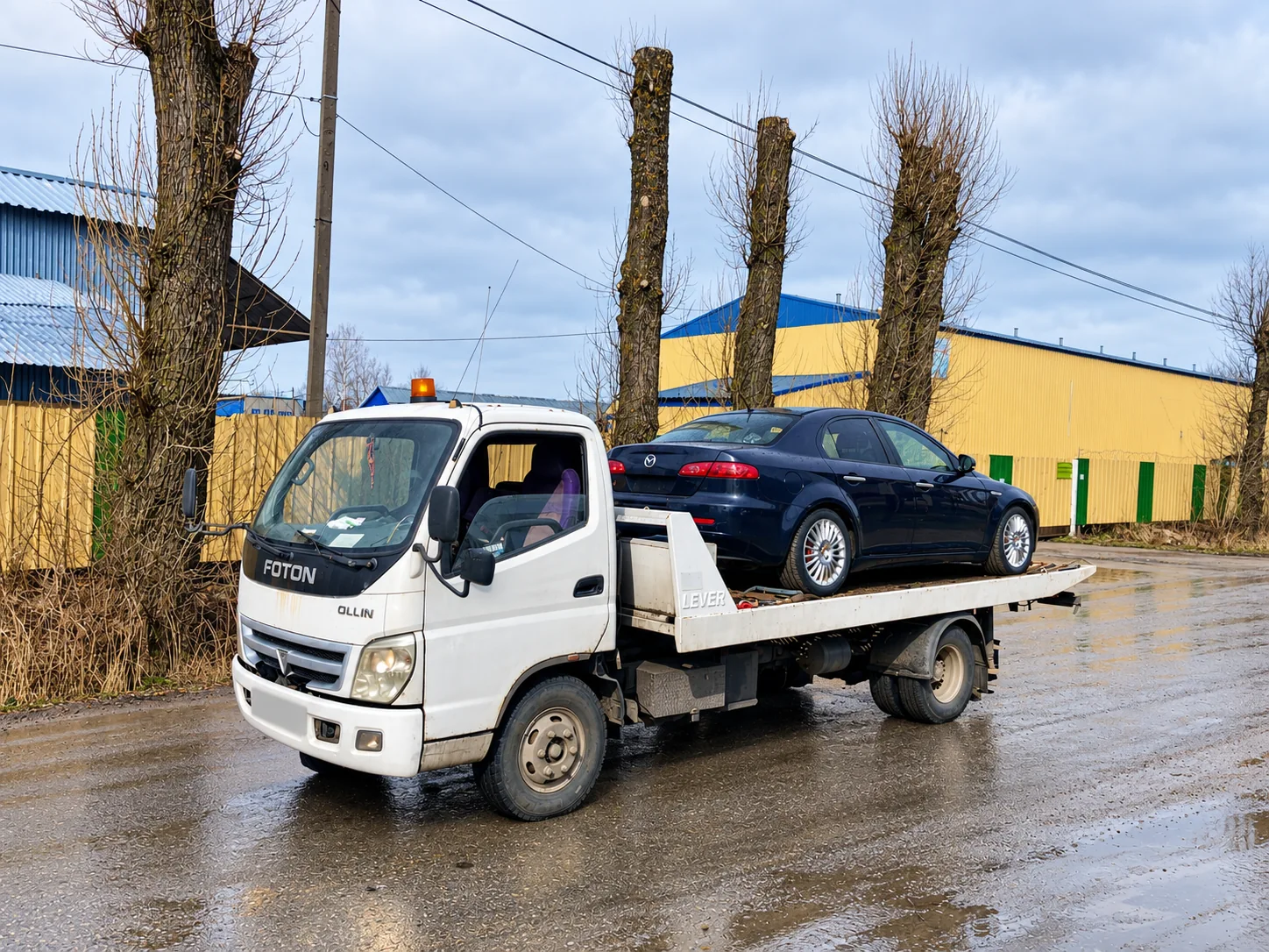 Эвакуатор с тёмным седаном на городской улице