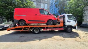 Эвакуация красного коммерческого фургона на платформе эвакуатора в Кобоне